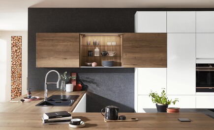Perfektes Zusammenspiel von Farben und Licht. Die matte alpinweiße Küche und die dunkle Wand fassen Arbeitsplatte und Schränke aus Holzoptik optimal ein. Tolles Extra: Wandschrank mit Schiebetüren, der durch seine Innenbeleuchtung mehr Behaglichkeit bringt. Perfektes Zusammenspiel von Farben und Licht. Die matte alpinweiße Küche und die dunkle Wand fassen Arbeitsplatte und Schränke aus Holzoptik optimal ein. Tolles Extra: Wandschrank mit Schiebetüren, der durch seine Innenbeleuchtung mehr Behaglichkeit bringt.